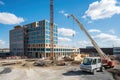 construction site with crane lifting load of materials onto a new building