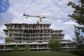 Construction site with cranes and green grass and cloudy sky Royalty Free Stock Photo