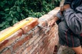 Construction site details - builder working with hands, level and trowel and building brick walls