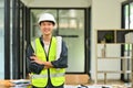 Construction site engineer wearing reflective vest standing with arms crossed and smiling to camera Royalty Free Stock Photo