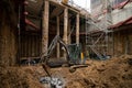 Construction site excavation with temporary propping, concrete piles, digger and temporary stair