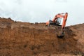 The construction site excavator digs a deep pit. Construction machinery. Excavation at a construction site