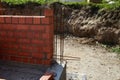 A construction site features a newly built brick wall with visible rebar bars extending from the concrete foundation Royalty Free Stock Photo
