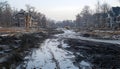 muddy construction site with partially built houses on both sides and muddy road with tire tracks and puddles in a suburban area Royalty Free Stock Photo
