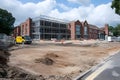 construction site with scaffolding on a large brick building and cleared ground area under a partly cloudy blue sky Royalty Free Stock Photo