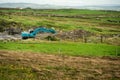 Construction site in a field with blue color excavator working. Dark dramatic sky,