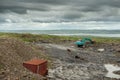 Construction site in a field with blue color excavator working. Dark dramatic sky, West of Ireland