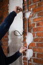 construction site, the hands of the master install a metal guide for plastering a brick wall close-up Royalty Free Stock Photo