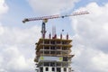 Construction site. A large construction crane against a blue sky builds a house. A high-rise building is under construction Royalty Free Stock Photo