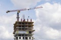 Construction site. Large industrial tower crane with unfinished tall building on blue skies with clouds as a background Royalty Free Stock Photo