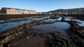 muddy construction site with large puddles and tire tracks near residential buildings on a clear sunny day with workers Royalty Free Stock Photo