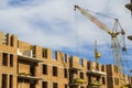 Construction site of a new apartment high building with tower cranes against blue sky. Residential area development. Real estate p