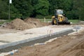 Construction site of new road in city. Yellow tractor. Piles of excavated ground. Royalty Free Stock Photo