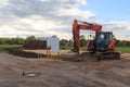 Construction site for one family house filled with sand, empty sign with copy space and digger in building area after earthworks, Royalty Free Stock Photo