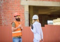 Construction site safety inspection. Discuss progress project. Woman inspector and bearded brutal builder discuss Royalty Free Stock Photo
