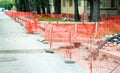 Construction site safety net fence as barrier parallel with the pipeline trench on the street in the city .