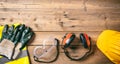 Construction safety. Protective hard hat, headphones, gloves and glasses on wooden background, copy space, top view Royalty Free Stock Photo