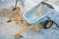 Construction site with a sand shovel and a wheelbarrow for transporting dry cement mix