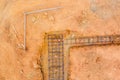 Construction site showing rebar framework and foundation work in progress on a dry, rocky terrain