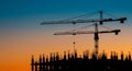 Construction Site Silhouettes at Sunset Two Tower Cranes and Building Framework AI generated. Royalty Free Stock Photo