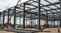 Construction Site: Steel Frame Structure Under Construction with Cranes Workers and Equipment Against a Cloudy Sky Royalty Free Stock Photo