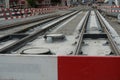 Construction site of a street-car line, embedding of metal rails in a concrete base with a barrier planks for security.