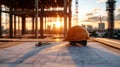 Construction site at sunset with blueprint and helmet symbolizing engineering and development Royalty Free Stock Photo