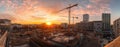 Construction site at sunset with cranes and buildings under an orange sky Royalty Free Stock Photo