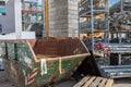 On  construction site, a waste container stands next to a shelf with scaffolding parts Royalty Free Stock Photo