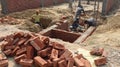 The construction site where a group of labourers are building the foundation of a structure with bricks and cement.