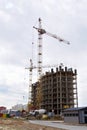 A construction site on which construction of a new multystoried house is carried out. Tower cranes