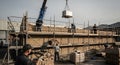 Construction Site Workers Lifting Materials On Scaffold Structure Under Cloudy Sky for Building Project with Safety Equipment and Royalty Free Stock Photo