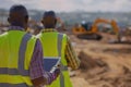 Construction site with workers overlooking a developing urban landscape under bright daylight Royalty Free Stock Photo