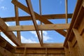 Construction of small wooden frame house. View from below on beams and roof rafters on the background of blue sky Royalty Free Stock Photo