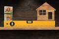 Construction Spirit Level with Roll of Euro Banknotes and a Model House