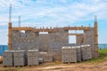 Construction stages. Cinder block house with protruding fittings, ground floor. Building material stacked on pallets Royalty Free Stock Photo