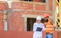 Construction team communication concept. Woman engineer and builder communicate construction site. Discuss progress plan