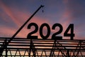 Construction team sets numbers for New Year 2024. Black silhouette staff works as a to prepare to welcome the new year 2024 Royalty Free Stock Photo