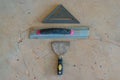 Construction tools background of palette knife, square and gauge on concrete