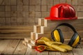 Construction tools leather gloves earphones and red helmet on wooden background Royalty Free Stock Photo