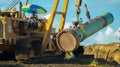 Construction work- the crane lifting the beam in the field and the workers looking at it Royalty Free Stock Photo