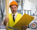 Construction work lifestyle portrait of young happy and attractive engineer or building contractor holding blueprints wearing Royalty Free Stock Photo