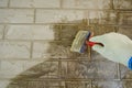 A construction worker applies paint to a brick wall.The painter paints primers the walls with a brush, makes repairs in the house