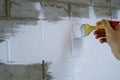 A construction worker applies paint to a brick wall.The painter paints primers the walls with a brush, makes repairs in the house