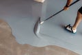 Worker apply grey epoxy resin in an industrial warehouse