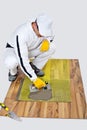 Construction worker applyes tile adhesive on wooden floor