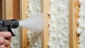 Construction worker applying insulation foam to a wall, focused, indoor work environment Royalty Free Stock Photo