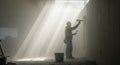 Construction Worker Applying Plaster on Wall Bathed in Dramatic Sunlight Royalty Free Stock Photo