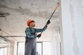 Construction worker applying plaster on walls and ceilings using telescopic handle Royalty Free Stock Photo