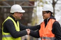 Construction worker and Asian architect shaking hands on construction site Royalty Free Stock Photo